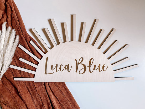 Half-sun wooden Luca Blue nursery name sign with engraved script and radiating rays.