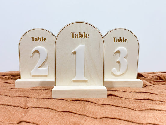 Three arched wooden table-number signs with raised white numbers 2, 1 and 3.