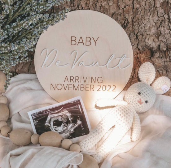 Baby McNault pregnancy announcement plaque beside an ultrasound picture and crocheted rabbit.