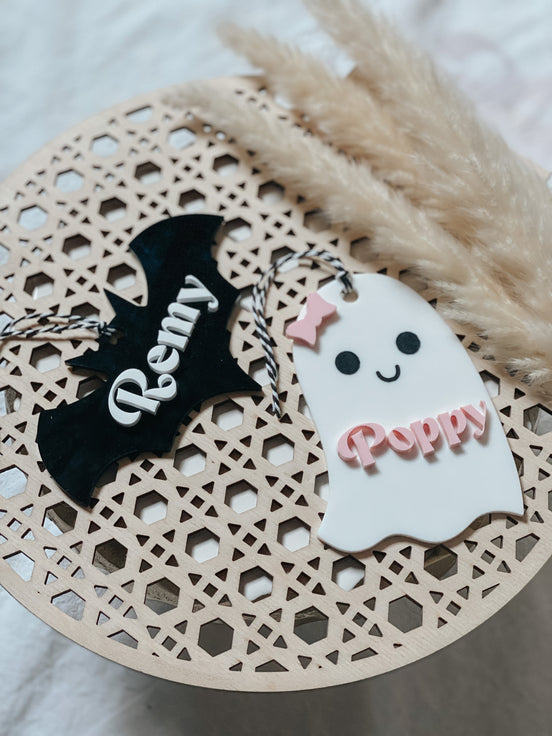 Personalized black bat and white ghost tags with raised name lettering and hanging cords.
