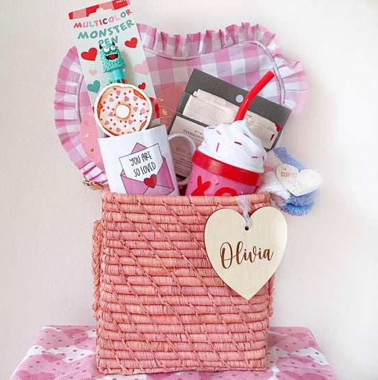 Wooden Olivia heart tag tied to a pink woven Valentine gift basket.