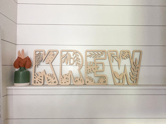Front view of KREW name letters with jungle leaf and plant cutouts.
