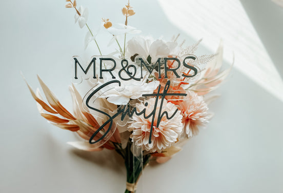 Full view of a clear wedding cake topper with raised Mr and Mrs Smith lettering.