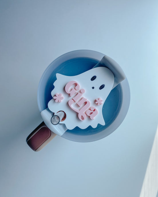White ghost tumbler topper personalized with pink Evie lettering and flower accents on a cup lid.