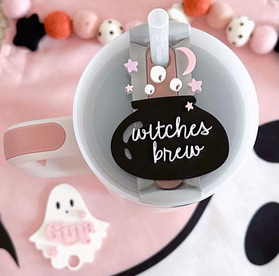 Black Witches Brew cauldron topper with pink moon and star details on a tumbler lid.