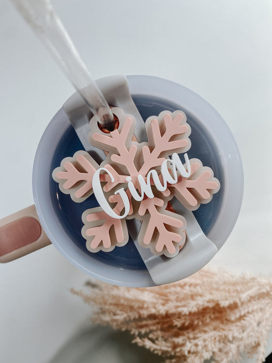 Pink snowflake tumbler topper personalized with white Grace script lettering.