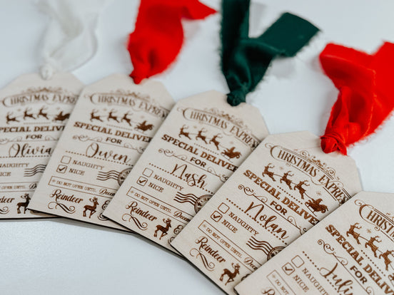 Personalized wooden Santa delivery gift tags with engraved checklists and red, green and white ribbons.