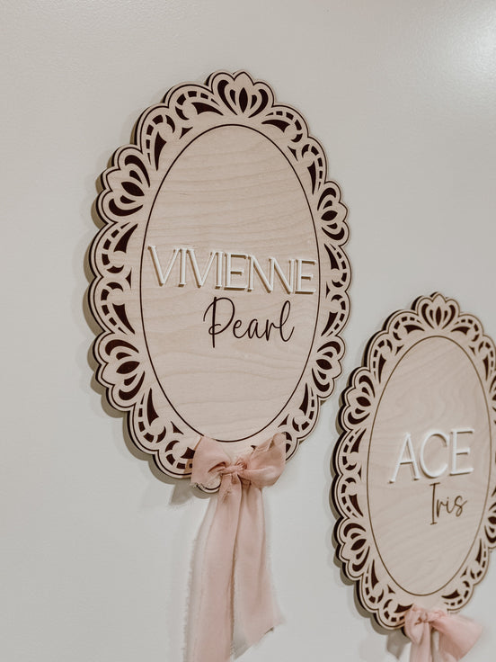 Close-up of ornate wooden frames and mixed lettering on Vivienne Pearl and Ace Ives name plaques.