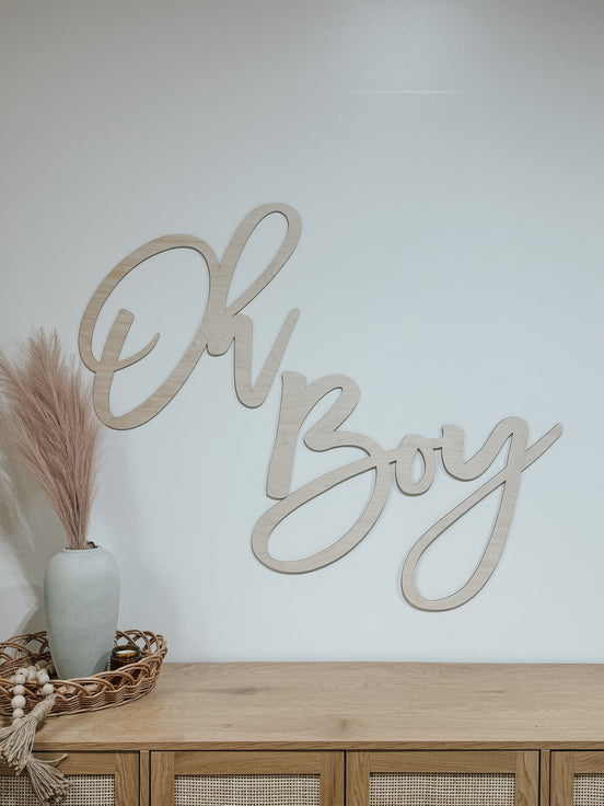 Natural wood Oh Boy script sign on a wall above a sideboard.