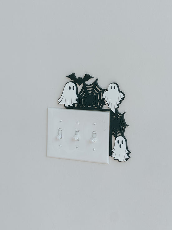 Angled view of the ghost-and-spiderweb corner decoration around a switch plate.