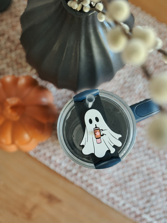 White ghost holding an orange drink, fitted as a topper on a dark-blue tumbler.