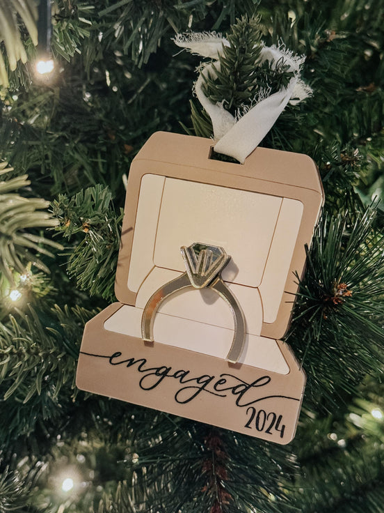 Angled close-up of the layered engagement ring and Engaged 2024 lettering on a ring-box ornament.