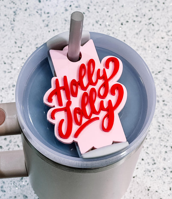 Red Holly Jolly lettering on a pink topper fitted around a tumbler straw.