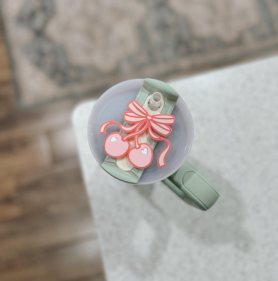 Overhead close-up of the layered cherries and striped bow on a tumbler lid.