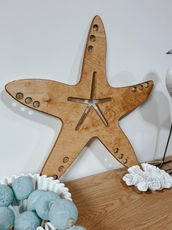 Close-up of an engraved wooden starfish with a central star and circular details along its arms.