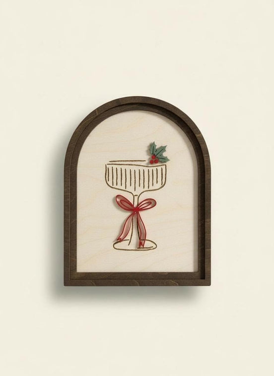 Front view of a Christmas cocktail sign with a dark arched frame and raised red bow.