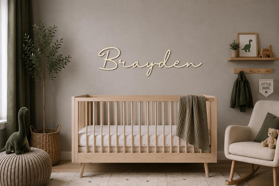 Brayden wooden script name sign above a natural wood crib in a neutral nursery.