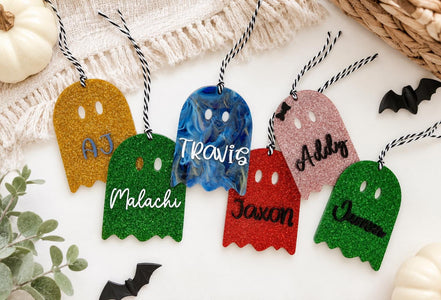 Personalized glitter and marble ghost tags in gold, blue, pink, green and red with hanging cords.