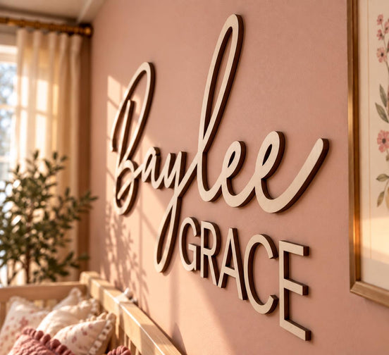 Close-up of raised wooden Baylee script and Grace block lettering on a pink nursery wall.